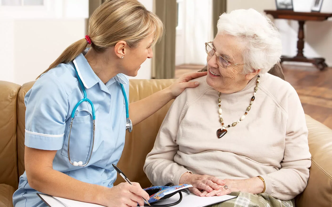 in home care aide sitting with elderly woman