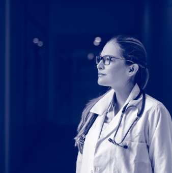 A doctor wearing a white coat and stethoscope stares into the distance