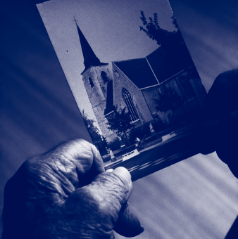 Two hands hold a photograph of a church